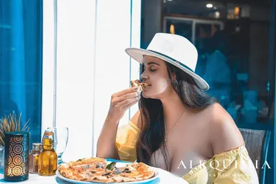 a woman sitting at a table eating a pizza at HOTEL ALKQUIMIA in Bayahibe