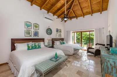 a bedroom with two beds and a living room at Stunning Villa with Private Pool and Jacuzzi in Casa de Campo in La Romana