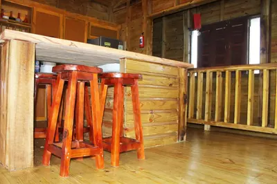 a couple of stools sitting under a bar in a cabin at Estancias Arroyazo in Constanza