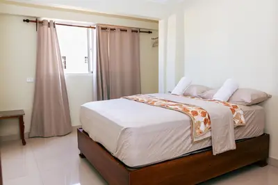 a bedroom with a bed with white sheets and a window at Modern 1-Bedroom Apartment with Terrace 300 Mbps Wi-Fi Near SDQ Airport in La Viva
