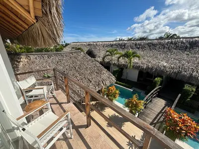 a balcony of a house with chairs and a thatch roof at TAKUMA BOUTIK HOTEL in Las Terrenas