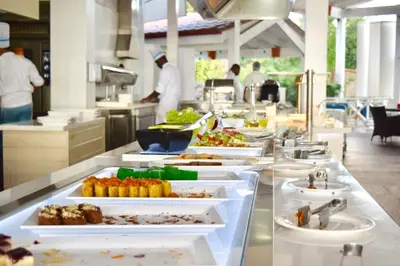 a buffet line with plates of food in a restaurant at 3BR Apt @CadaquesCaribe Bayahibe in San Rafael del Yuma