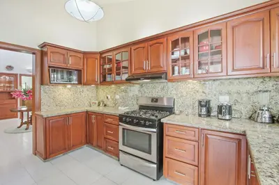 a kitchen with wooden cabinets and a stove top oven at Amazing Villa in Casa de Campo with Included in Price Maid and Waiter in La Romana