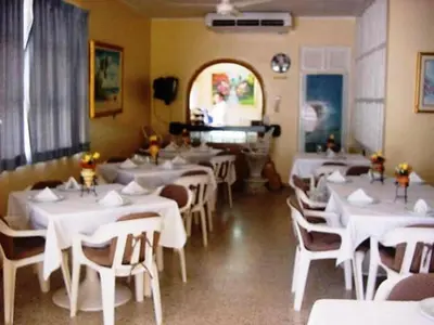 a restaurant with white tables and chairs and a piano at Hotel Caribe in Santa Cruz de Barahona