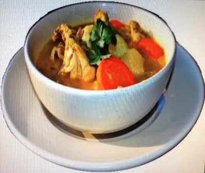 a bowl of chicken noodle soup on a plate at Hotel Caribe in Santa Cruz de Barahona