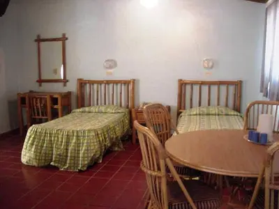 a room with two beds and a table and chairs at Hotel Caribe in Santa Cruz de Barahona