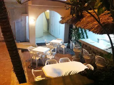 a restaurant with white tables and chairs and a palm tree at Hotel Caribe in Santa Cruz de Barahona