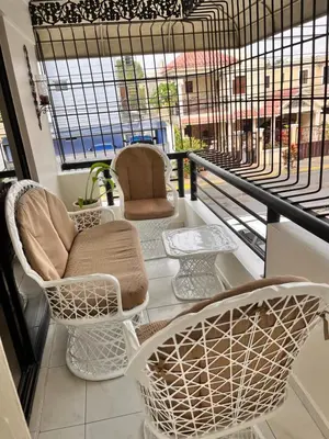 a balcony with chairs and tables and a window at Apartamento amueblado en Villa Olga in Santiago de los Caballeros