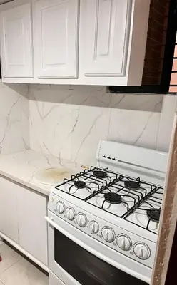 a white kitchen with a stove and white cabinets at Apartamento amueblado en Villa Olga in Santiago de los Caballeros