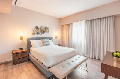 a bedroom with a large bed and a table at Fully Serviced Apartment at Regatta Living - 3B in Santo Domingo