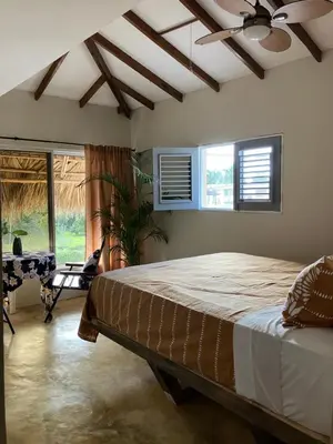a bedroom with a large bed with a ceiling fan at Yes Papa! Rooms only 100m from the beach! in Las Galeras