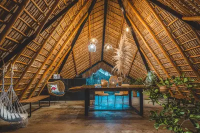 a dining room in a bamboo building with a table and chairs at Green Land Bubble Glamping in Cabarete