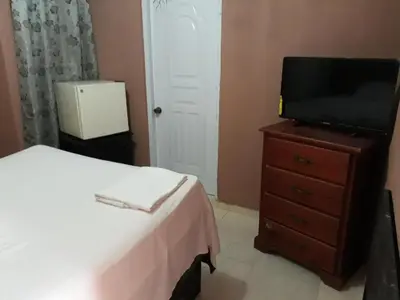 a bedroom with a bed and a television on a dresser at Apartahotel Next Nivel - Queen room with Ac in Punta Cana