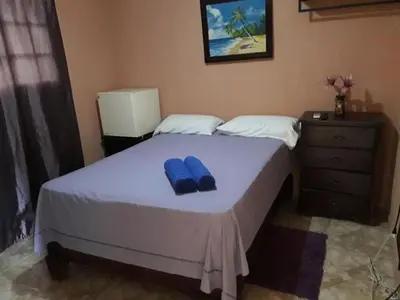 a bedroom with a bed with two blue slippers on it at Apartahotel Next Nivel - Queen room with Ac in Punta Cana