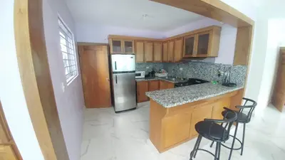 a kitchen with a refrigerator and two bar stools at Apartamento amueblado en Santiago, Res Blue Amber, 2 habitaciones in Santiago de los Caballeros