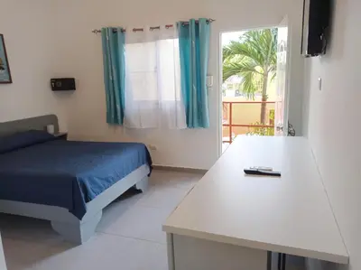 a bedroom with a bed and a table and a window at Hotel Casa Coco in Boca Chica