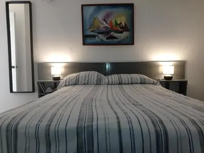 a bedroom with a bed with a striped comforter and two lamps at Hotel Casa Coco in Boca Chica