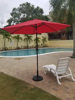 a red umbrella sitting next to a chair and a pool at Cerro Altos jardin 809-488-8618 in Santiago de los Caballeros