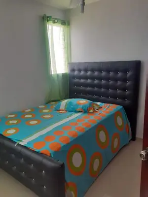 a bedroom with a bed with an orange and blue comforter at Cerro Altos jardin 809-488-8618 in Santiago de los Caballeros