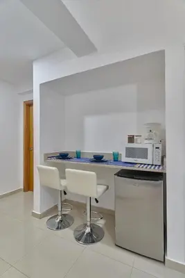 a kitchen with two white chairs and a counter at Sunset View 2BR Apartamento Juan Dolio Las Velas in Juan Dolio