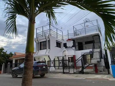 a car parked in front of a house with a palm tree at 6A Cozy Apt in Santiago Center - Great Stay in Santiago de los Caballeros