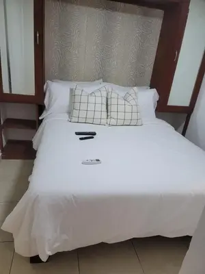 a large bed with white sheets and pillows at small apartment in Santo Domingo
