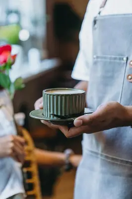 a person holding a coffee cup on a plate at Regatta Living Hotel By Mint in Santo Domingo
