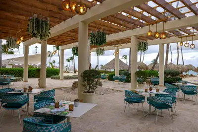 a restaurant with blue chairs and tables on the beach at JOIA Bavaro by Iberostar - Adults Only All Inclusive Resort in Punta Cana