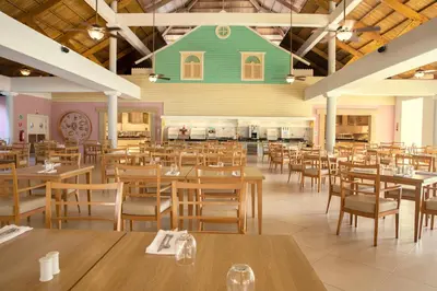 a restaurant with wooden tables and chairs and a green house on the ceiling at Iberostar Waves Punta Cana - All Inclusive in Punta Cana