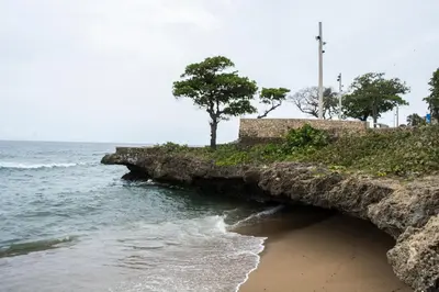 a rock wall next to the ocean with a beach at Malecon Cozy Private Room in Santo Domingo