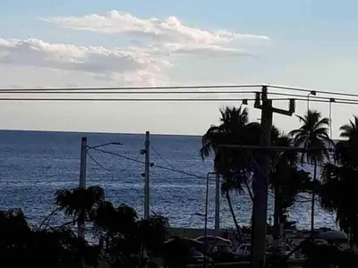 a view of the ocean with a palm tree at Malecon Cozy Private Room in Santo Domingo