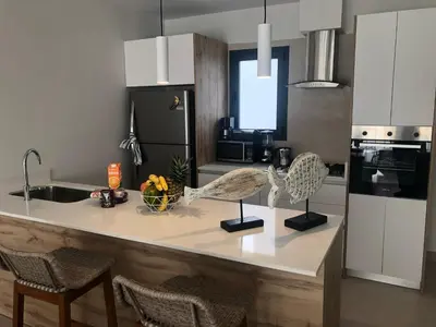 a kitchen with a counter with chairs and a sink at Hermoso Penthouse a solo pasos de la Playa in Punta Cana