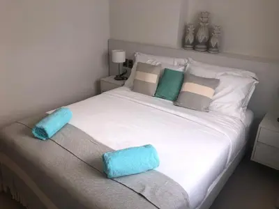 a white bed with two blue pillows on it at Hermoso Penthouse a solo pasos de la Playa in Punta Cana