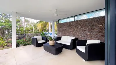 a patio with black and white chairs and a brick wall at Villa Isha - modernist hideaway at Cap Bonita in Las Terrenas