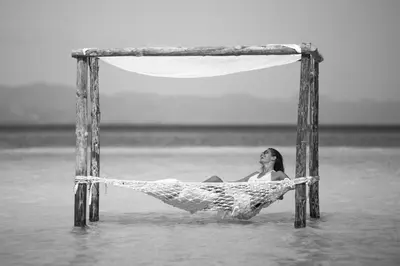 a woman laying in a hammock in the water at Punta Rucia Lodge Hotel Boutique & Spa in Punta Rucia