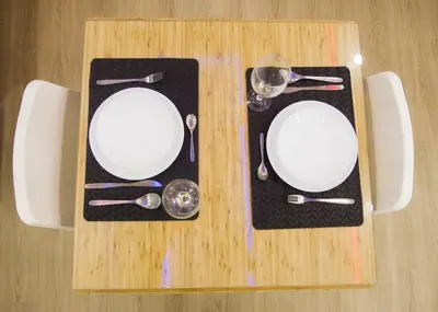 a wooden table with two white plates and silverware at Estancia Casa Real Frente a la Zona Colonial in Calero