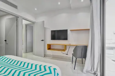 a bedroom with a bed and a desk and a television at Monaco Residences Piantini in Santo Domingo