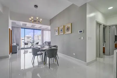 a dining room and living room with a table and chairs at Monaco Residences Piantini in Santo Domingo