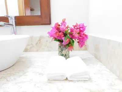 a vase filled with pink flowers on a bathroom counter at Beach Residence | Escapada Penthouse Vista Mar in Punta Cana