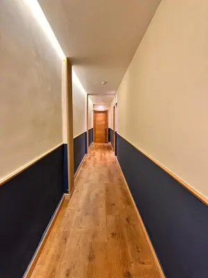 a long hallway with blue walls and a wooden floor at Hotel La Colonia in Santo Domingo