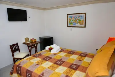 a bedroom with a bed and a table and a television at Hotel Los Jardines in Santiago de los Caballeros
