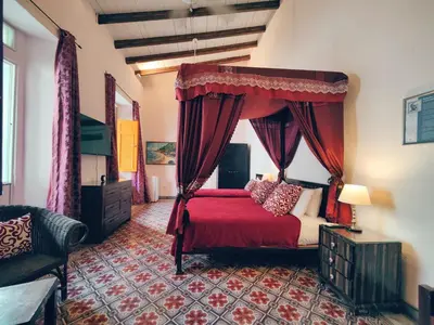 a bedroom with a red bed with a canopy at Hotel Boutique Casa Sánchez in Santo Domingo