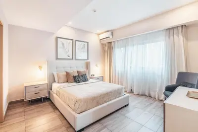 a white bedroom with a bed and a chair at Fully Serviced Apartment at Regatta Living II - 302 in Santo Domingo