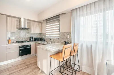 a kitchen with a counter and two chairs at a kitchen island at Fully Serviced Apartment at Regatta Living II - 302 in Santo Domingo