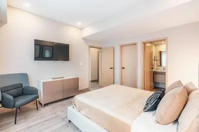 a bedroom with a bed and a chair and a television at Fully Serviced Apartment at Regatta Living II - 302 in Santo Domingo