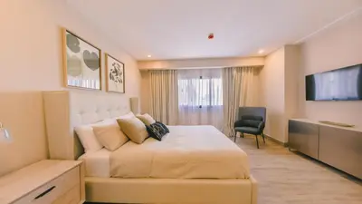 a bedroom with a bed and a couch and a television at Fully Serviced Apartment at Regatta Living II - 905 in Santo Domingo