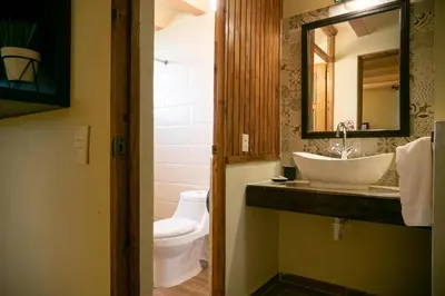 a bathroom with a sink and a toilet and a mirror at Hotel Altocerro in Constanza