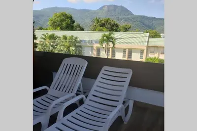 two white chairs on a balcony with mountains in the background at Great location, right downtown Puerto plata . in San Felipe de Puerto Plata