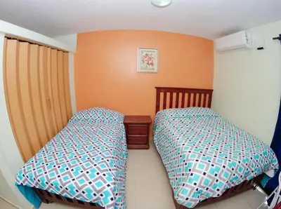 two beds in a small bedroom with orange walls at Hotel Renacer in Santo Domingo
