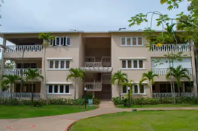 a large building with palm trees in front of it at Apartment Monocal in Boca Chica in Boca Chica